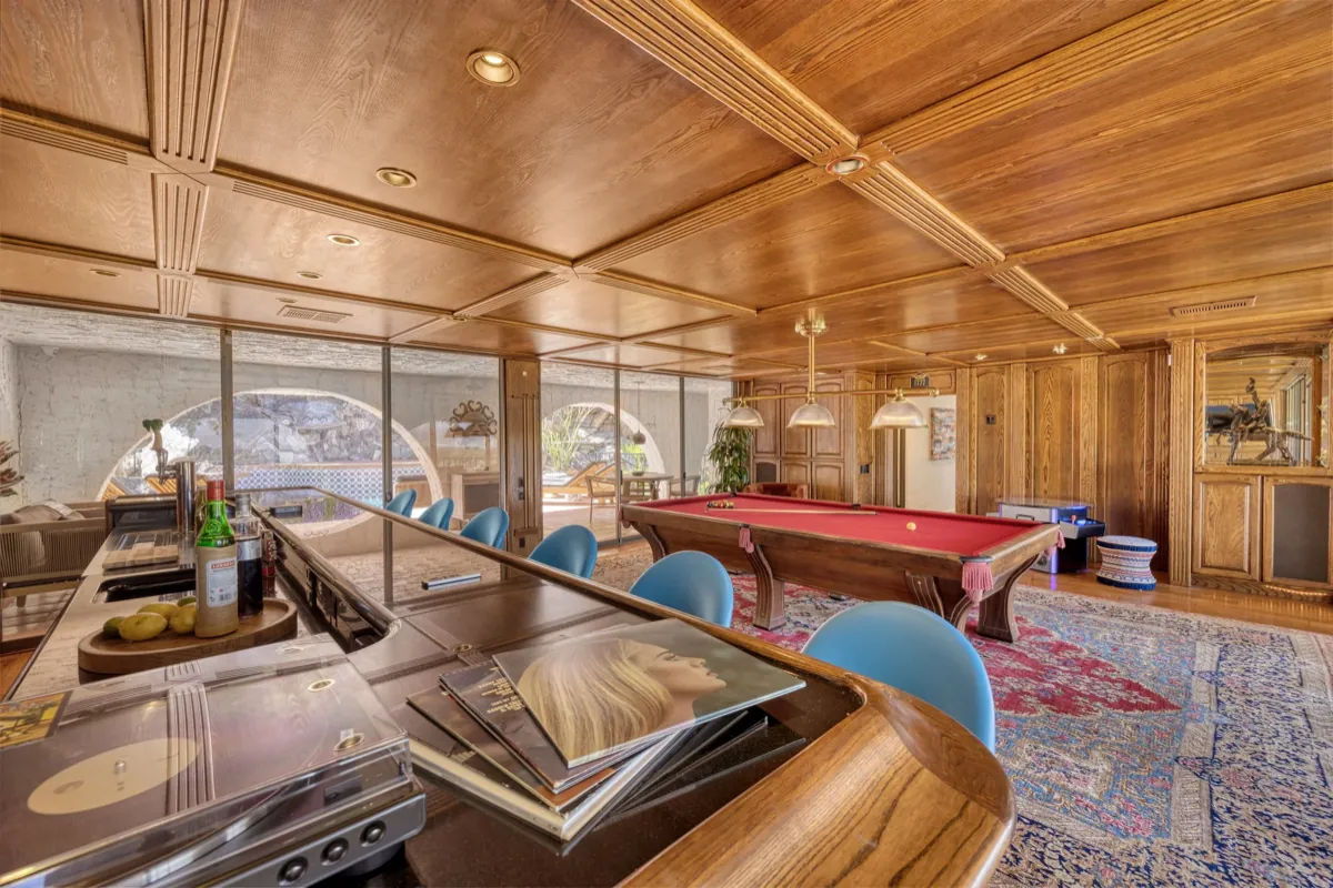 View across the saloon bar top toward the billiards table and the pool terrace beyond.