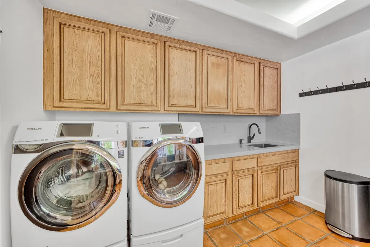 Laundry room with a side-by-side washer and dryer under maple cabinets.