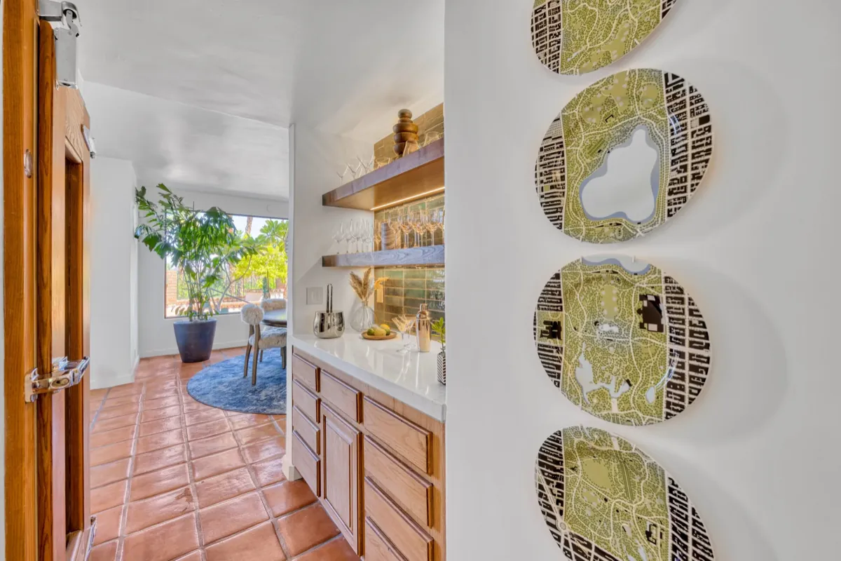Hallway with a built-in wood bar cabinet and a row of woven gold wall discs.