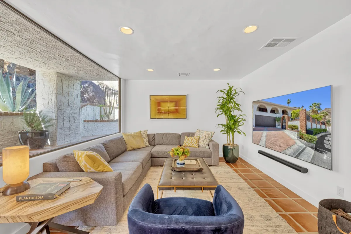 Family room with a deep sectional, swivel chair and mounted television beside a picture window.