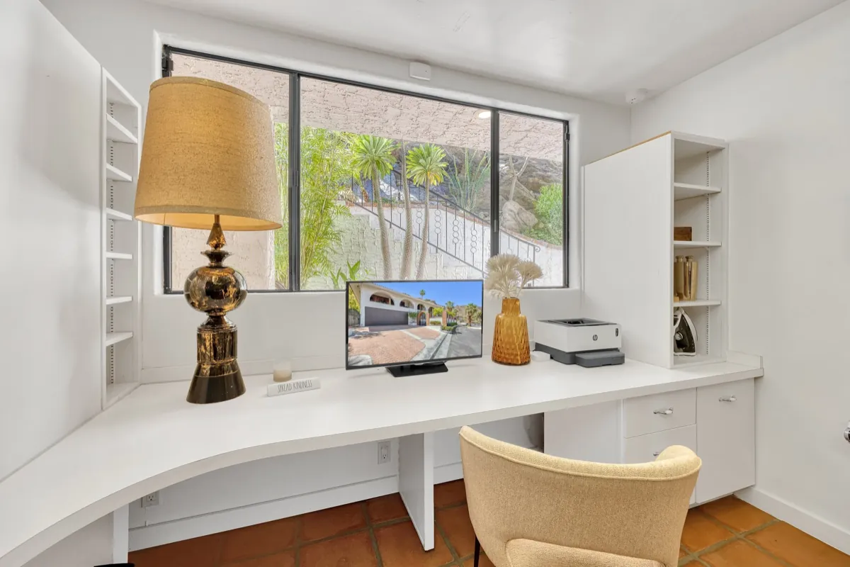 Built-in desk nook with a brass lamp and a window over the desert garden.
