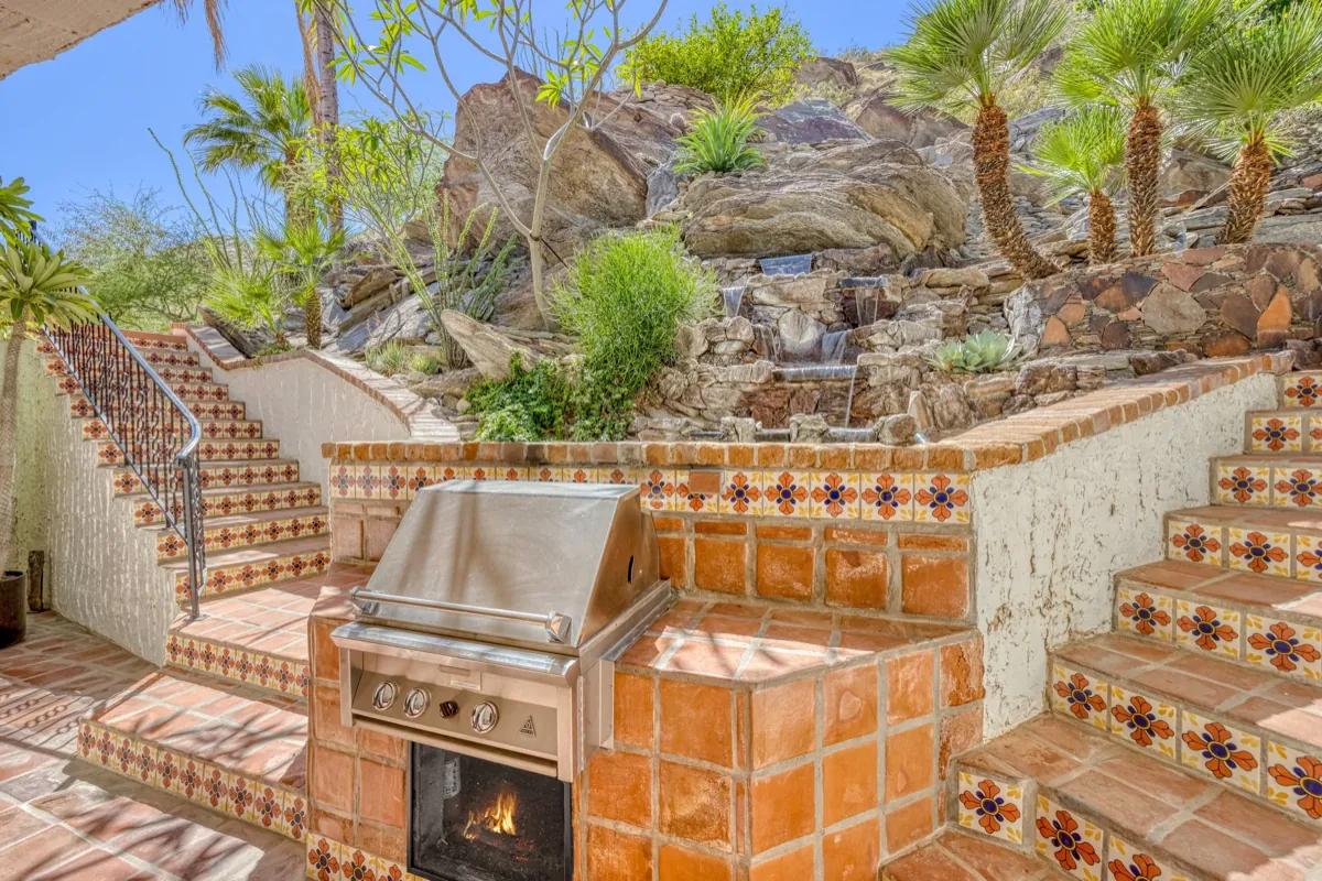 Tiled outdoor stair and built-in grill with a fire feature, cut into the rock garden.